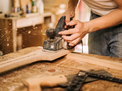 Artisan menuisier travaillant sur une fenêtre en bois, utilisant un rabot manuel pour ajuster le châssis